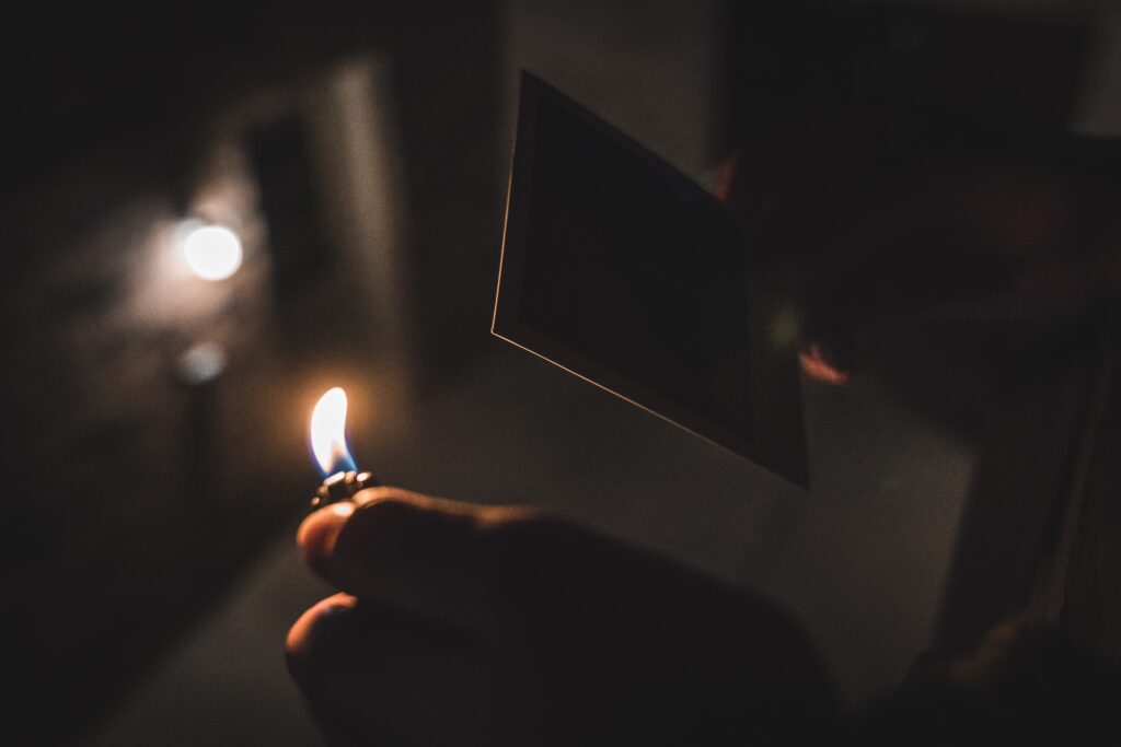 A person lighting fire to an old photo of their ex as a coping mechanism for love.